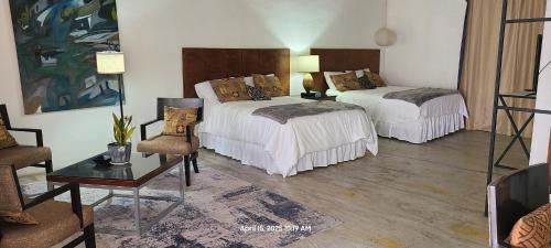 a bedroom with two beds and a table and chairs at Hotel suites Las Abuelas in Copán Ruinas