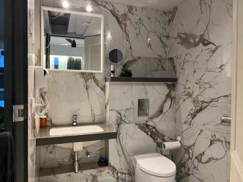 a bathroom with a toilet and a sink and a mirror at Aerovista Suites - Neon Homeotel- 1 kms from Airport in Pune