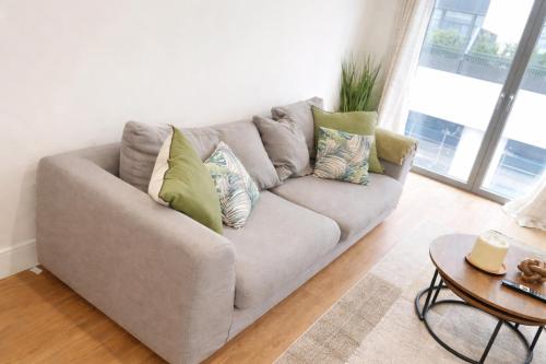 a gray couch in a living room with a table at Zone 1 Bright and Modern 3 Bed Apt Hyde Park Central London in London