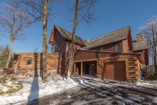 a log home with a garage in the snow at WISPer by Railey Vacations in McHenry