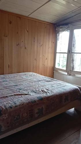 a bed in a room with wooden walls and windows at Departamento interior centro de el tabo in El Tabo