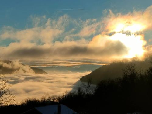 a view of the sun rising over a sea of clouds at L'Horizon - Maison en Pierres, Vue Alpes et Nature in La Burbanche