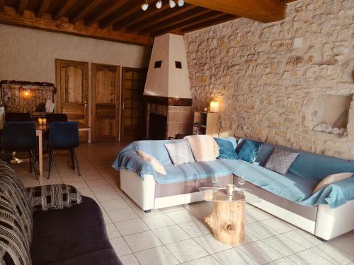 a living room with a couch and a stone wall at L'Horizon - Maison en Pierres, Vue Alpes et Nature in La Burbanche