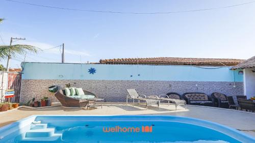 a swimming pool with chairs and a couch on a patio at Suite em Guriri Norte com Piscina e Academia in São Mateus