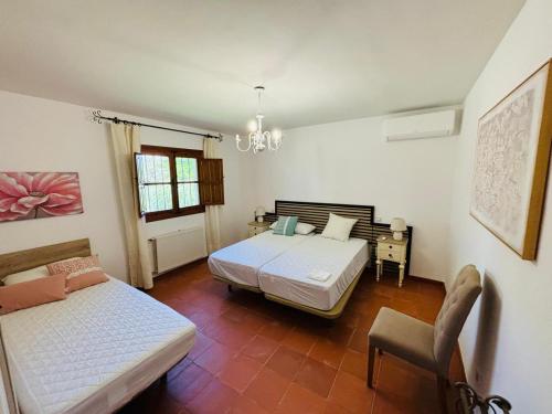 a bedroom with two beds and a chair in it at Dehesa La Parrilla - VUT- Eventos in Pepino