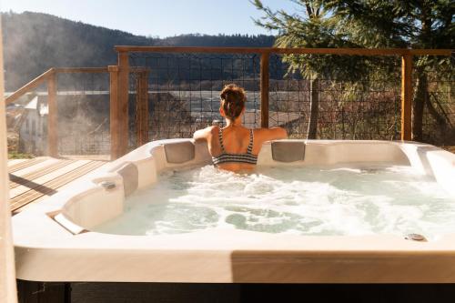 a woman is sitting in a hot tub at Les Terrasses du Grillon in Chambon-sur-Lac