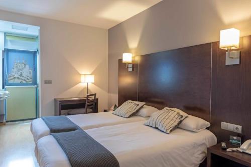 a hotel room with two beds and a desk at Hotel Cardeña by gaiarooms in Burgos