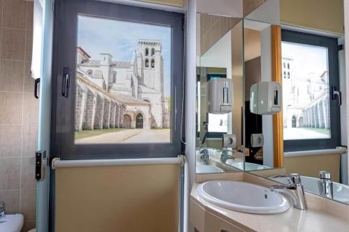 a bathroom with a sink and a mirror and a building at Hotel Cardeña by gaiarooms in Burgos