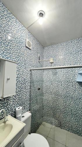 a bathroom with a shower and a toilet and a sink at Pousada Manancial in Itaúnas