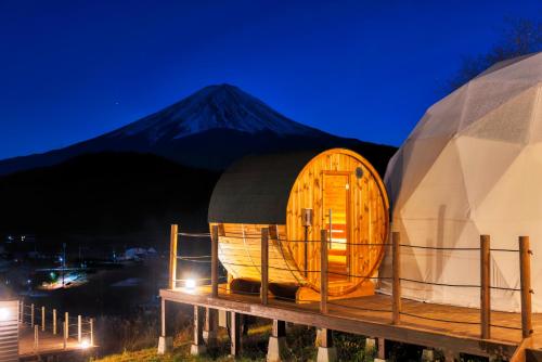 a wooden cabin with a mountain in the background at グランファーム富士河口湖 Granfarm Fujikawaguchiko in Fujikawaguchiko