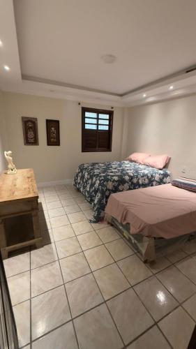 a bedroom with two beds and a table in it at Casa maricota in Porto Seguro