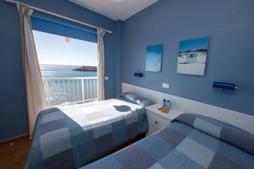 a bedroom with two beds and a view of the ocean at Pensión La Gaviota in Playa de Santiago
