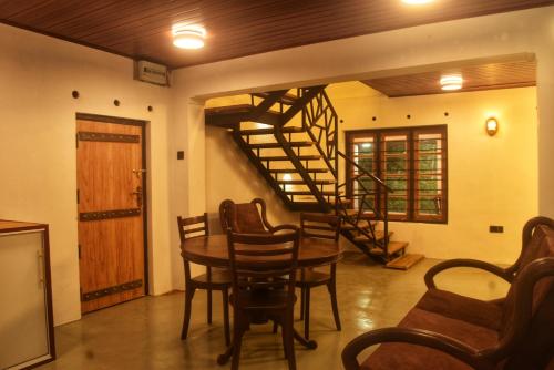 a dining room with a table and a spiral staircase at Patrius Bungalow by Daddy's Nest in Diyatalawa