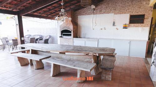 a large wooden table and benches in a room at Suite em Guriri Norte com Piscina e Conforto in São Mateus