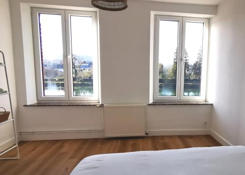 an empty room with three windows and a bed at La Maison Trente in Chooz