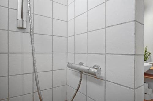 a shower with a hose attached to a white tiled wall at 3000-Stege-Stejlepladsen-13 in Stege