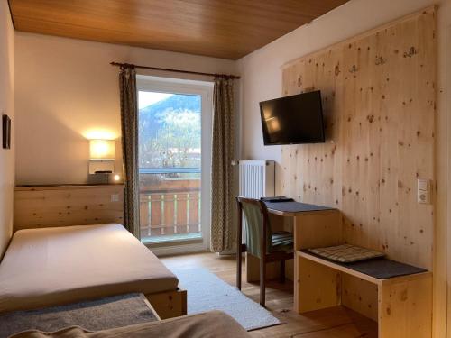 a bedroom with a bed and a desk and a window at Gästehaus Margarita in Raubling
