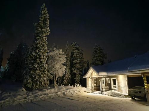 a house in the snow at night at Hietavilla Aurora - Hot tube - Sauna - AC - Fireplace - 11kW EV-refuel - Landscape view - Silence - Free WiFi in Ruka