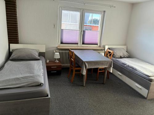a room with two beds and a table and a desk at Freundliche Monteurwohnung in Bad Oldesloe