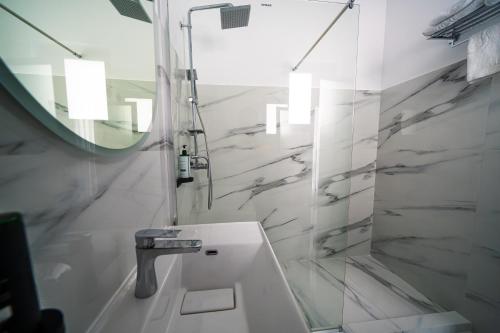 a white bathroom with a sink and a mirror at Sunrise Rooms in Bucharest