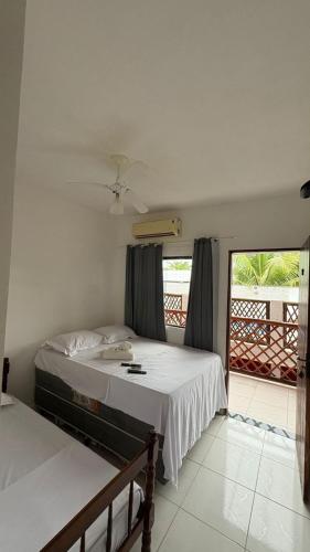 a bedroom with two beds and a balcony at Pousada Manancial in Itaúnas