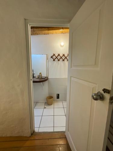 a bathroom with a white tile floor and a door at Refugio Alana Máncora in Máncora