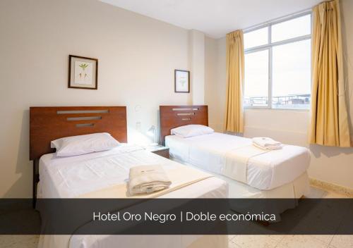 two beds in a hotel room with a window at Hotel Oro Negro in Talara
