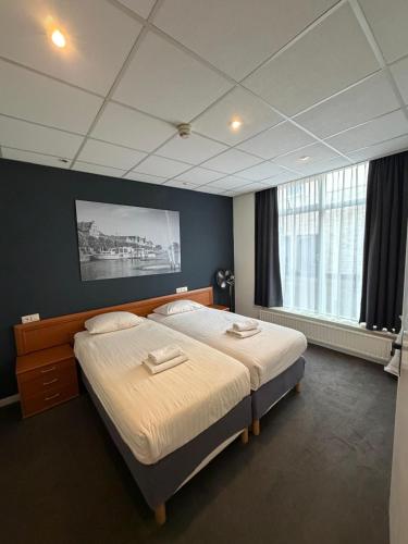 a bedroom with two beds and a large window at Hotel & Appartementen Royal in Sas van Gent