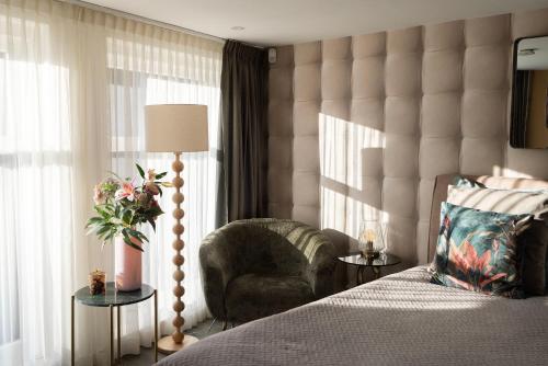 a bedroom with a bed and a chair and window at City Attic Haarlem in Haarlem