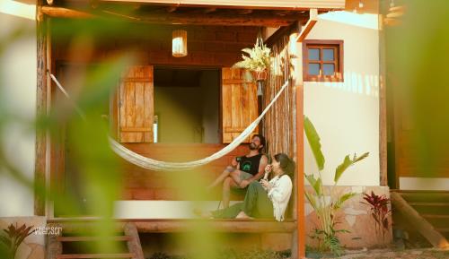 two people sitting on the porch of a house at Chalés VerdeSer in Sêrro