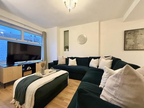 a living room with a green couch and a television at 2 bed house secure parking Sleeps 6 in Ipswich