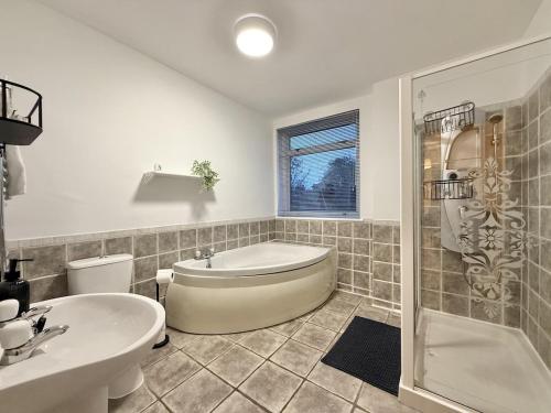 a bathroom with a tub and a toilet and a sink at 2 bed house secure parking Sleeps 6 in Ipswich