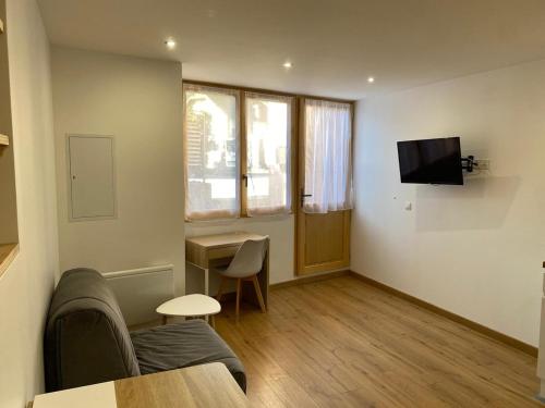 a living room with a couch and a tv at Studio avec toutes les commodités autour in Faverges