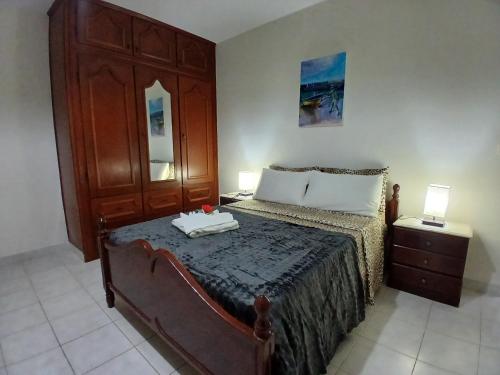 a bedroom with a bed with a wooden headboard and a table at ROMANA guest house in Tarrafal da Vila de Ribeira Grande