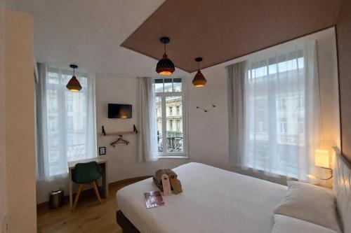 a bedroom with a white bed and two windows at HOTEL AMBASSADEUR in Lille