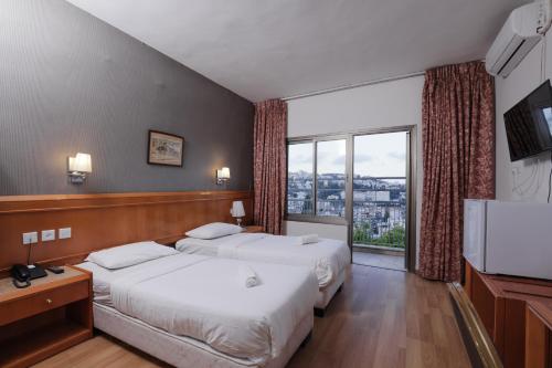 ナザレにあるTabar Hotelのベッドが2つと大きな窓があるホテルの部屋