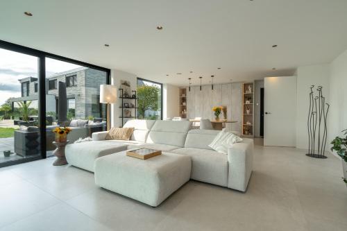 a living room with a white couch and a table at Oase 41 - 5 STAR location with Indoor swimming pool & unique landscape view in Sint-Laureins
