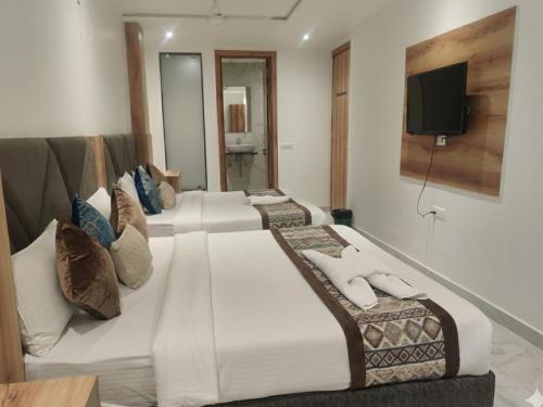 three beds in a room with a tv on the wall at Hotel Ravi Palace Agra in Agra