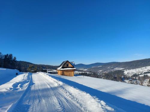 a snow covered road with a cabin in the distance at Góralska Przystań in Nowa Wieś