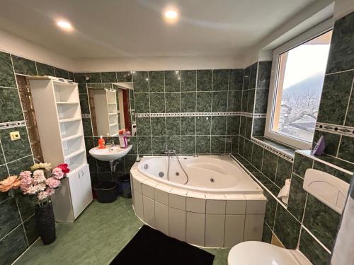 a green tiled bathroom with a tub and a sink at private house in Ústí nad Labem