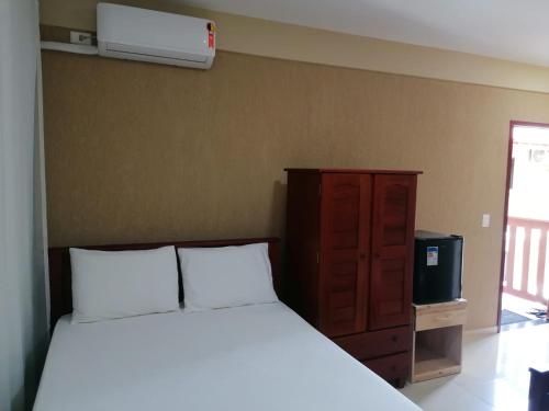 a bedroom with a white bed and a tv at Pousada Tropical dos Corais in Cabo de Santo Agostinho