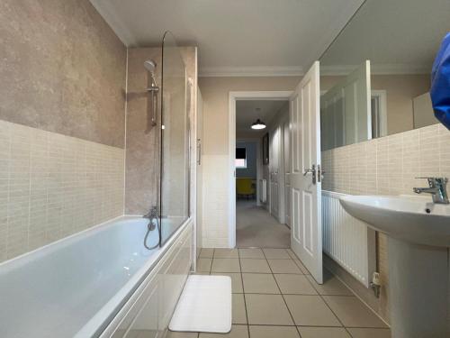 a bathroom with a bath tub and a sink at Siskin House in Wickham Market
