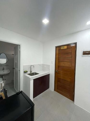a bathroom with a sink and a wooden door at Tanauan Transient Casa Joe in Daraza