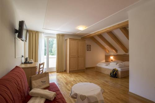 a living room with a bed and a couch at Hotel Erica in Tesero
