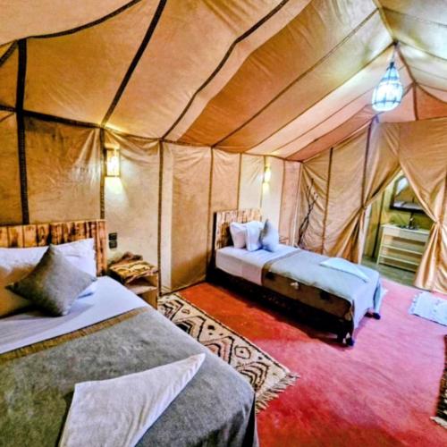 a bedroom with two beds in a tent at Magic Luxury Camp in Merzouga