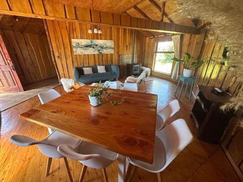 un soggiorno con un tavolo di legno e sedie bianche di Cabañas Kuela a Puerto Varas