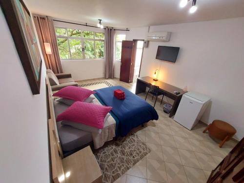 a bedroom with a bed with pink pillows and a desk at Pousada Casa Verde - Curitiba in Curitiba