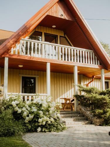 a wooden house with a balcony and some flowers at Viesu nams Smēdes in Limbaži