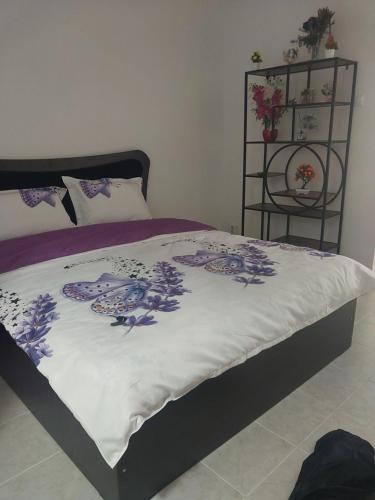 a bed with a white comforter with purple flowers on it at Studio Relax2 in Bacău