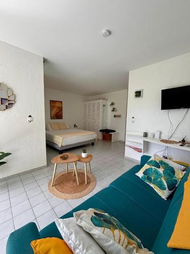 a living room with a blue couch and a table at La Kawannaise Blue Lagon - Piscine, Wifi, Plage, Terrasse in Grand-Bourg